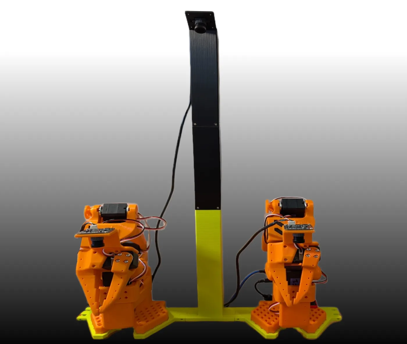 Zwei orange gedruckte SO-101-Roboterarme auf einer gelben Grundplatte, darüber ein schwarzer Mast mit einer Kamera, die von oben auf die Arme schaut